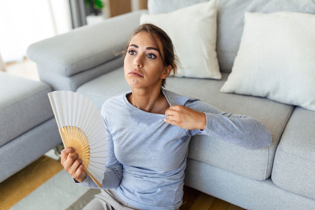 Sweating woman sitting on the floor fanning herself