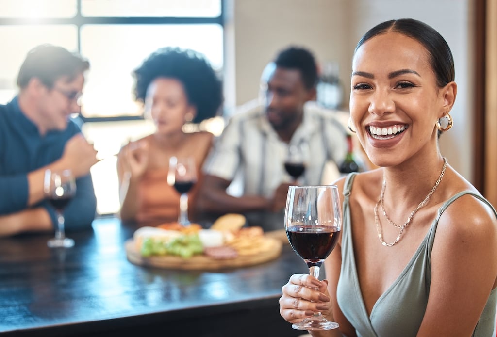 Woman smiling holding a wine glass with her friends in the background | Thermostat Services in Dallas, TX