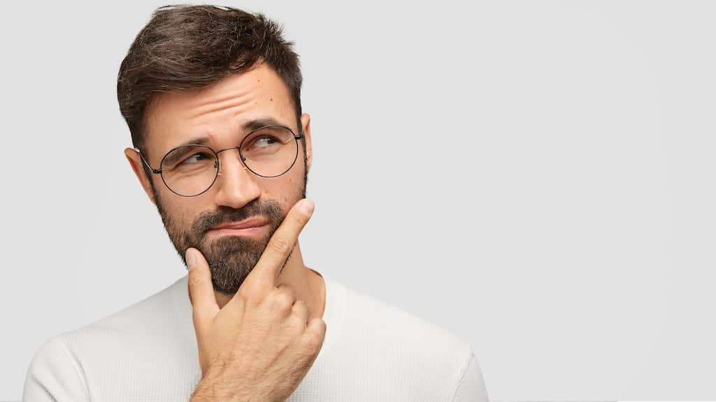 Man with glasses seeming deep in thought.