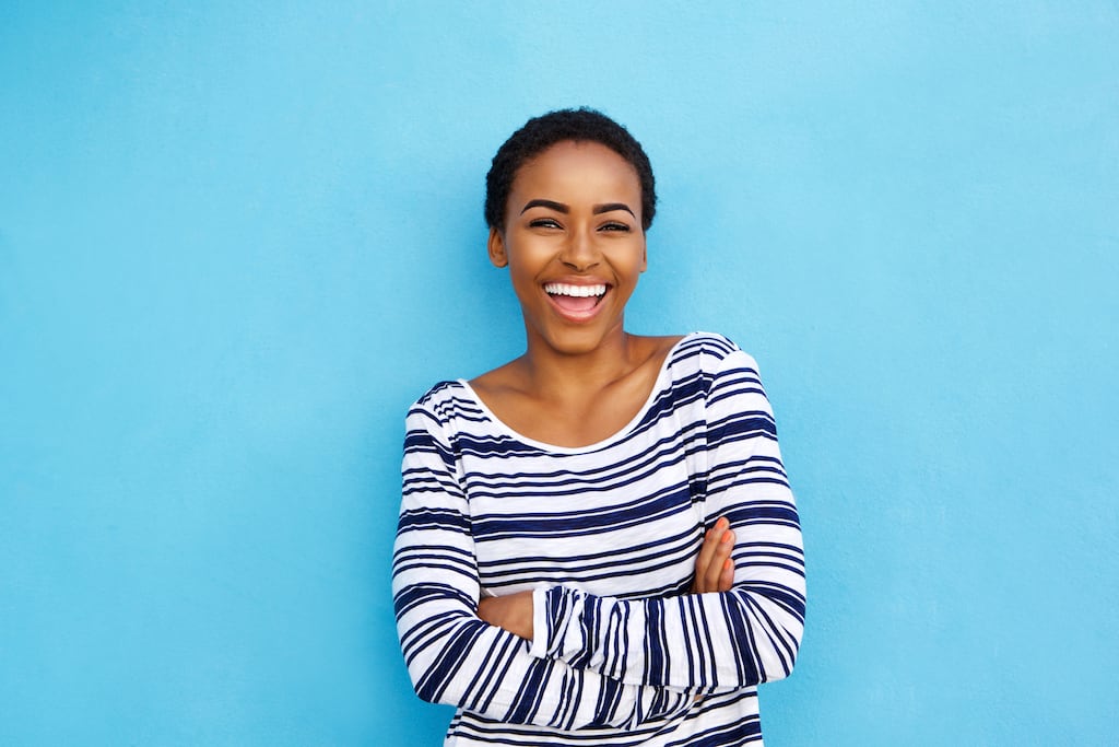 Woman smiling against a bright blue background | Thermostat Services in Dallas, Richardson, and The Colony, TX