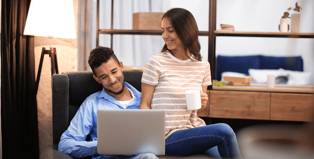 Young couple relaxing in their Dallas, TX home looking at a laptop drinking coffee | Allen, TX