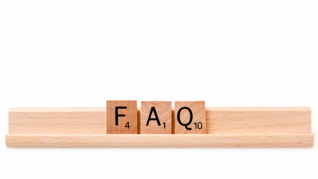 Scrabble game board Lettered wooden tiles forming the Words "FAQ" on white background. 