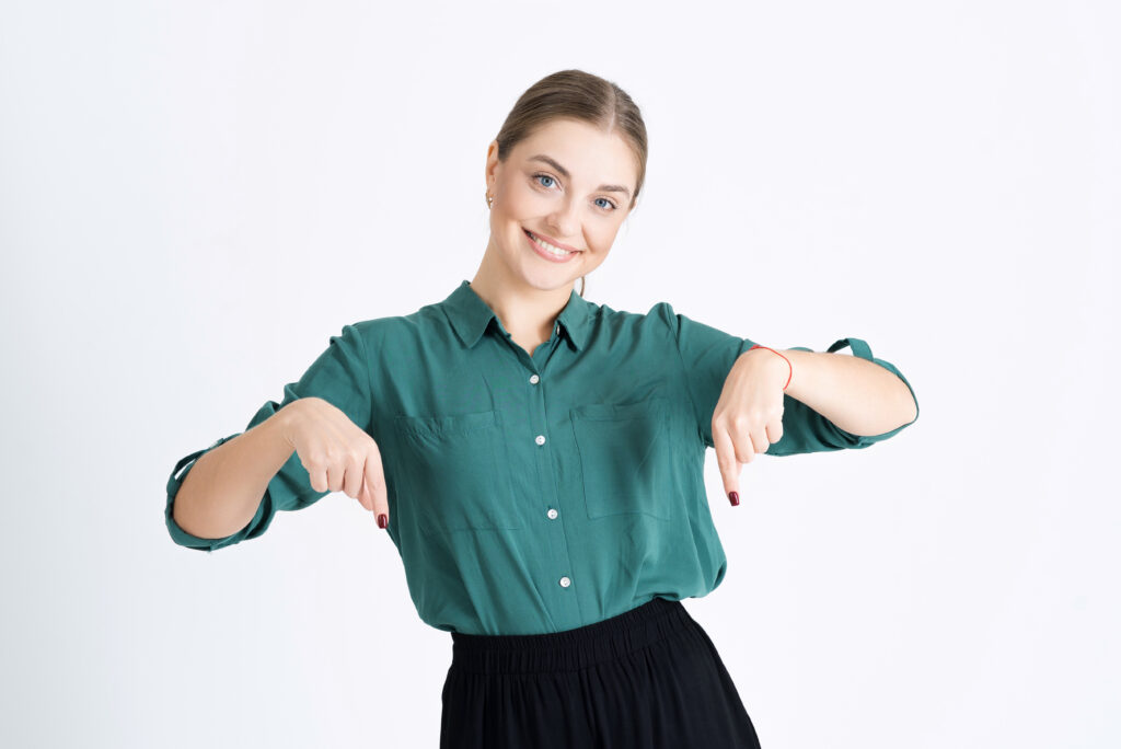 A woman points her fingers down at One Hour Air Conditioning & Heating of Dallas, experts in AC drain pan installation, for advertising. The scene is isolated on a white studio background.