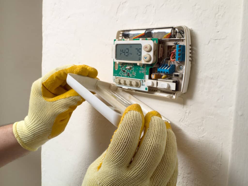 an air conditioning repairman performing maintenance work. Thermostat Repair Services in Dallas, TX