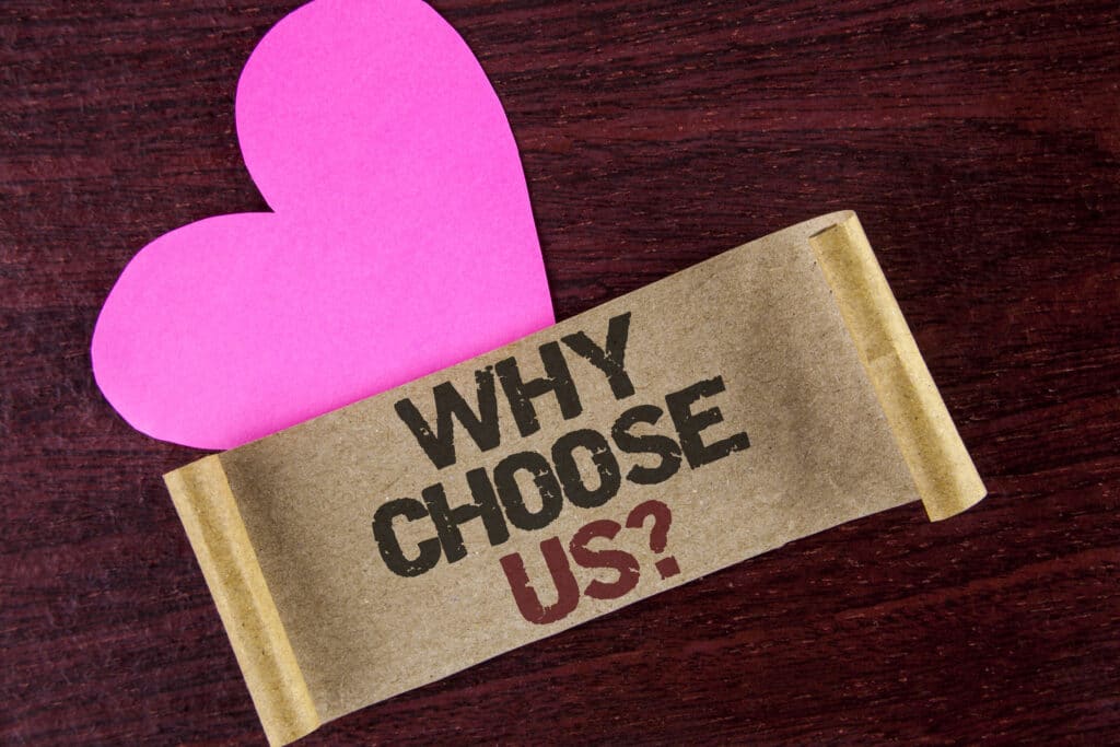 A writing note with the question 'Why Choose Us' written on cardboard paper against a wooden background, with a heart symbol next to it. Why Choose One Hour Air Conditioning & Heating of Dallas