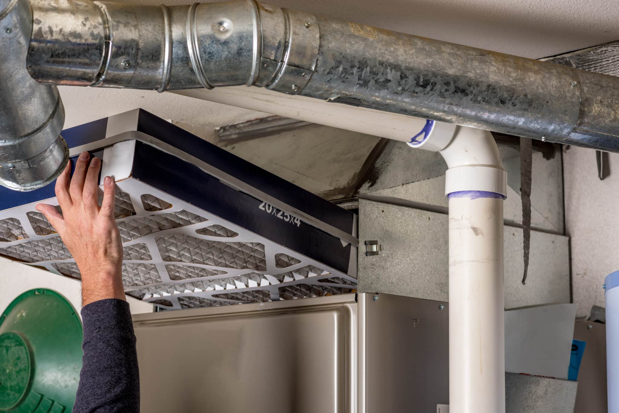 A man replaces the furnace filter with a clean one to prevent HVAC system damage.