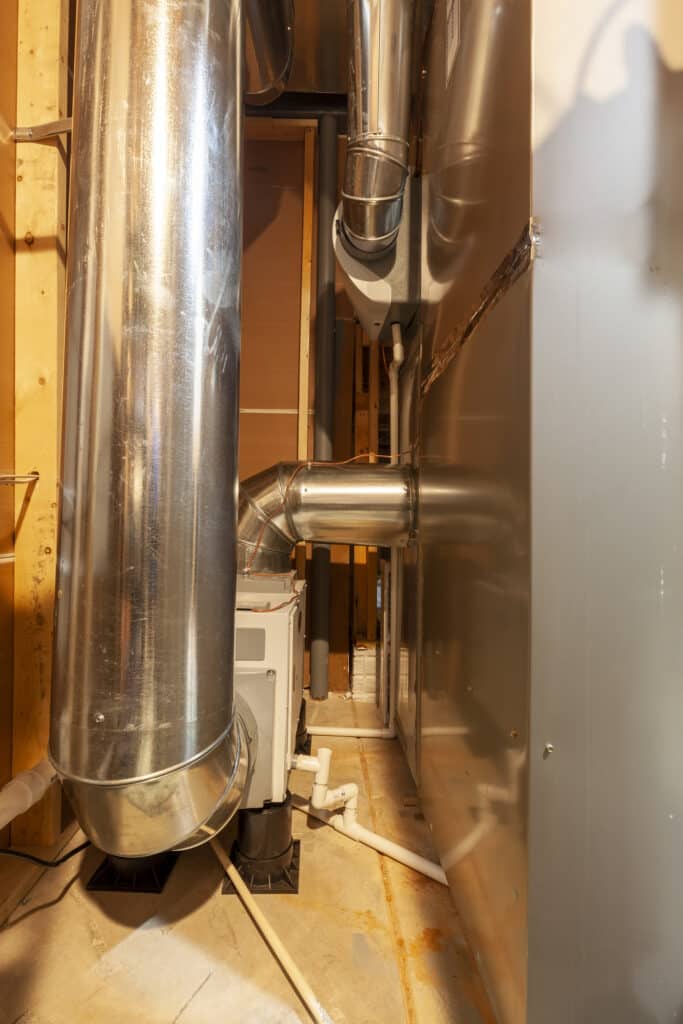 A whole-house heavy-duty dehumidifier with its duct attached to the HVAC furnace system of a house.