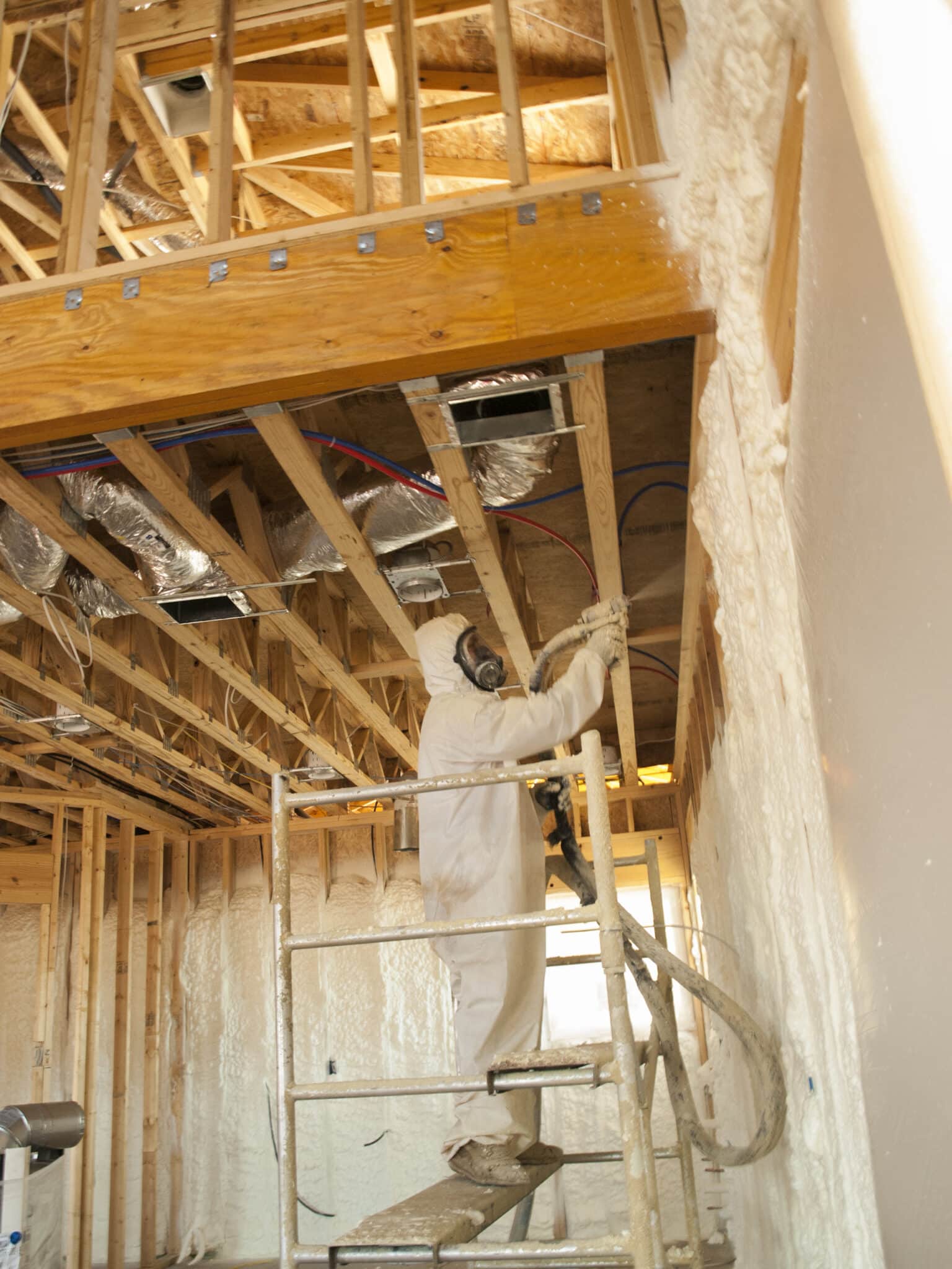 A worker applying polyurethane foam insulation, Insulation materials.