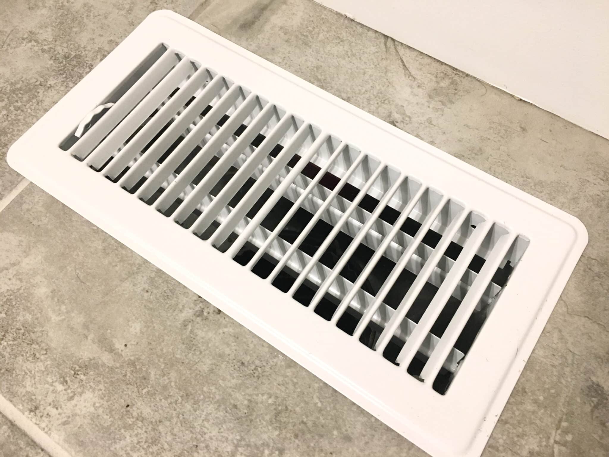 A white air vent cover floor register on square tiles, Air Filtration.