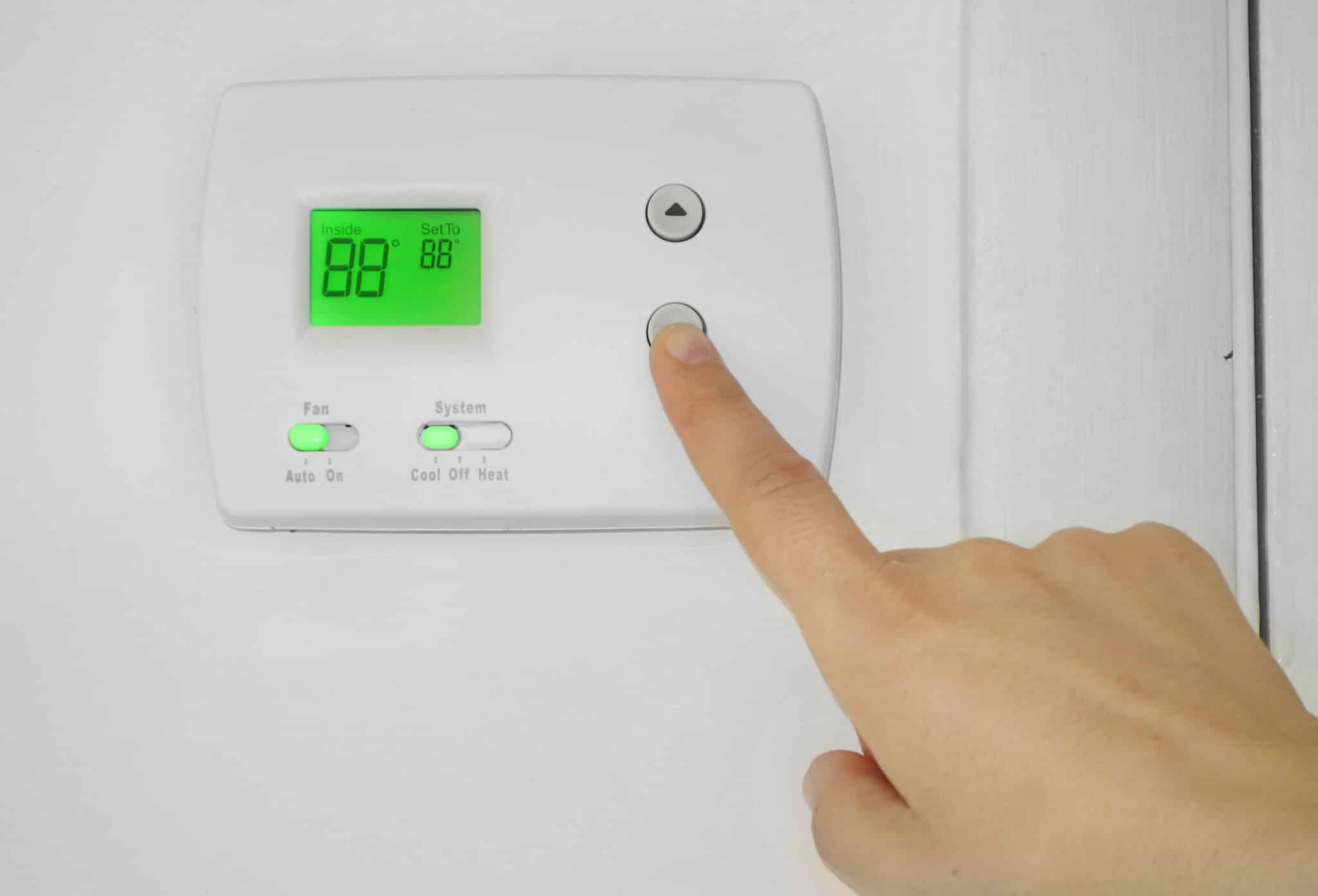 Person adjusting the AC thermostat temperature, HVAC.